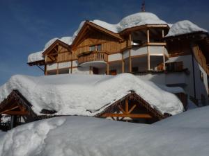 a snow covered house with a pile of snow at Hotel Ambiez in Andalo