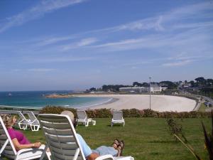 Trévou-TréguignecにあるLes Terrasses de la plage de Trestelの芝生の椅子に座ってビーチを眺めている二人