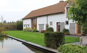 une maison avec un étang en face de celle-ci dans l'établissement B&B De Luyckhoek, à Handzame