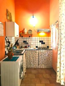 トラッペートにあるMelogranoのオレンジ色の壁のキッチン、洗濯機が備わります。