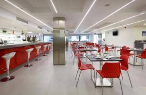 un restaurante con mesas y sillas rojas y un bar en Eurostars Central en Madrid