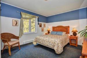 a bedroom with a bed and a chair and a window at Condo Lac Archambault 326 in Saint-Donat-de-Montcalm