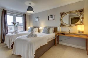 2 Betten in einem Zimmer mit einem Spiegel und einem Schreibtisch in der Unterkunft Carrick Retreat - Donnini Apartments in Ayr