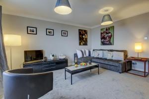 ein Wohnzimmer mit einem Sofa und einem TV in der Unterkunft Carrick Retreat - Donnini Apartments in Ayr