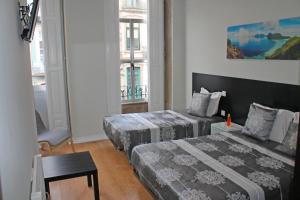 a hotel room with two beds and a desk at Lunar Guest House in Porto