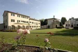 um grande edifício branco com um quintal com flores em Villa Toderini em Codognè