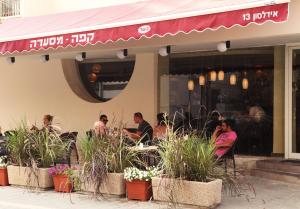 a group of people sitting outside of a restaurant at Idelson Hotel in Tel Aviv