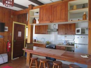 a kitchen with wooden cabinets and a counter with stools at Cabañas Donde La Oma in Villarrica