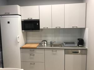 a kitchen with white cabinets and a sink and a microwave at Noclegi Mikołów in Mikołów