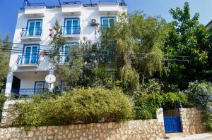 a white building with blue windows and a stone wall at Miramar Pansiyon in Kaş