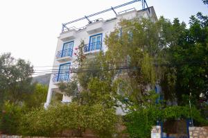 a white building with blue windows and trees at Miramar Pansiyon in Kaş