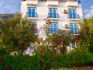 a white building with blue windows and flowers at Miramar Pansiyon in Kaş