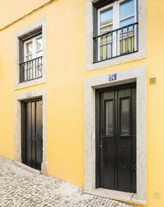 リスボンにあるGlory Days Lisbon Apartmentsの黒いドアと窓が二つある黄色い建物