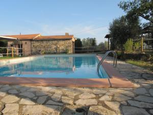 a swimming pool in a yard with a stone patio at Residenza D'Epoca Le Pisanelle in Manciano