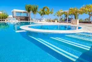 a swimming pool with blue water in a resort at Santorini Mesotopos in Fira