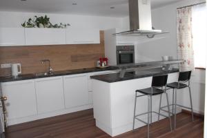 a kitchen with white cabinets and a counter with stools at Ferienwohnung by Josef Lanzinger in Bad Vigaun