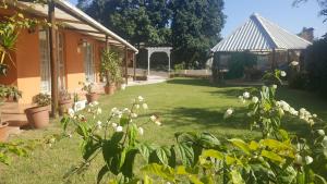 un jardin avec un kiosque en arrière-plan dans l'établissement Rose of Sharon, à Amanzimtoti