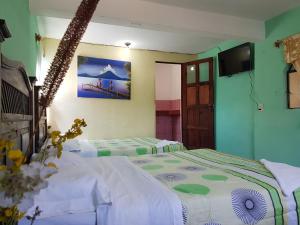 a room with two beds and a television in it at Hotel Los Angeles Panajachel in Panajachel