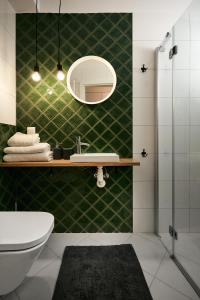 グダニスクにあるAlgo Apartmentsの緑のタイル張りのバスルーム(シンク、鏡付)
