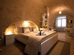 - une chambre avec un grand lit dans un mur en pierre dans l'établissement dormiRÈtrani, à Trani