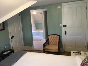 a bedroom with a bed and a chair and a bathroom at The Inn at Ragged Edge in Chambersburg