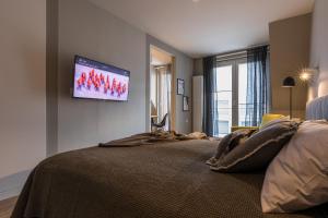 a bedroom with a bed with a flat screen tv on the wall at Tartaczna Street Apartment in Gdańsk