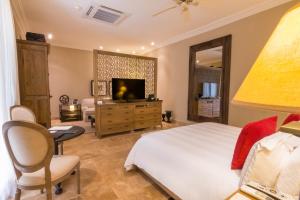 a bedroom with a bed and a television and a chair at Bastión Luxury Hotel in Cartagena de Indias
