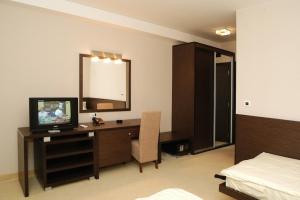 a bedroom with a desk with a television and a bed at Hotel Golf Luxury in Kruševac