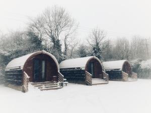 eine Gruppe von drei schneebedeckten Hütten in der Unterkunft The Norman Knight Whichford in Long Compton