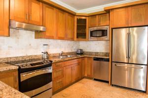 a kitchen with wooden cabinets and stainless steel appliances at Luxury Oceanview Condo 2 BR/2.5 BA in Sosúa