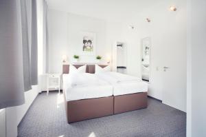 ein weißes Schlafzimmer mit einem Bett und zwei Spiegeln in der Unterkunft Hotel Löwenguth in Montabaur
