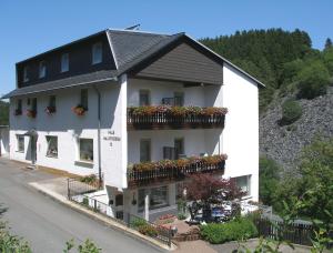 a white building with flower boxes on the balconies at Pension Haus Waldfrieden, MeineCardPlus inklusive in Willingen