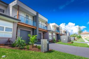 a row of apartment buildings with grass at Escape At Nobbys Executive Townhouse 1 74 Pacific Drive in Port Macquarie