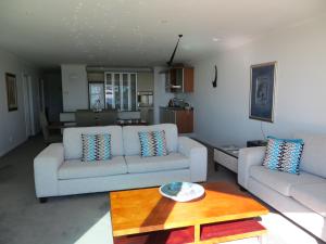 a living room with two couches and a table at Cutterscove Resort Apartments in Mount Maunganui