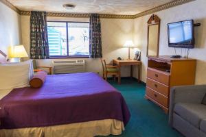 una camera d'albergo con letto e TV di Guest House Inn a Junction City