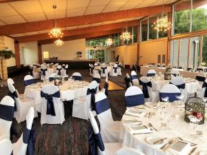 um grande salão de banquetes com mesas e cadeiras brancas em Macedon Ranges Hotel & Spa em Macedon