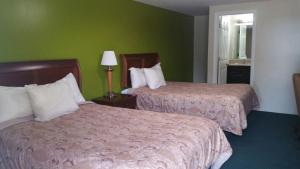 2 camas en una habitación de hotel con paredes verdes en Slumberland Motel Mount Holly, en Mount Holly