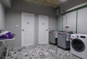a laundry room with three washing machines and a washer and dryer at Travelier Hostel in Bangkok