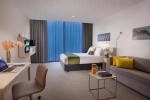 a hotel room with a bed and a couch at Citadines on Bourke Melbourne in Melbourne