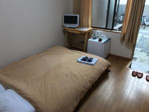 1 dormitorio con 1 cama y escritorio con TV en Minshuku Takenoya, en Naoshima