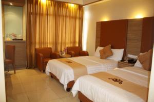 una habitación de hotel con 2 camas y una silla en Grand Pasundan Convention Hotel, en Bandung