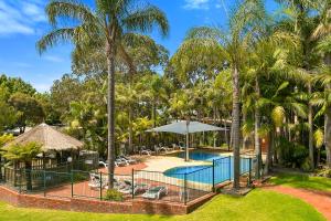 una imagen de la piscina del complejo con palmeras en Kaloha Holiday Resort Phillip Island en Cowes