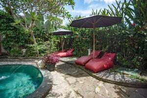 - un bain à remous avec des oreillers rouges et un parasol dans l'établissement Ladera Villa Ubud, à Ubud