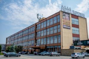 um grande edifício com carros estacionados num parque de estacionamento em Hotel Imperial Inn em Târgu-Mureş