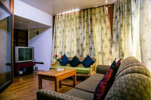 ein Wohnzimmer mit einem Sofa und einem TV in der Unterkunft Niraamaya Retreats Aradura Kohima in Kohīma