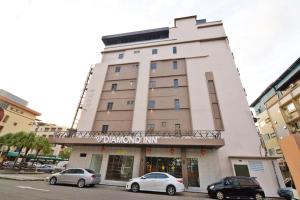 a tall building with cars parked in front of it at Diamond Inn in Kota Kinabalu