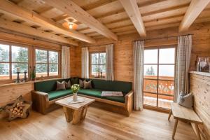 a living room with a green couch and windows at Prenner Alm in Haus im Ennstal
