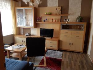 ein Wohnzimmer mit einem Schreibtisch, einem TV und einem Sofa in der Unterkunft Ferienwohnung Thale in Thale