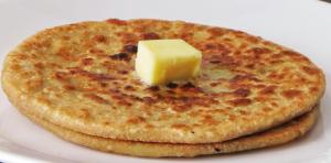 un piatto bianco con formaggio sopra un pancake di Kunjpur Guest House a Allahābād