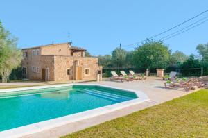a swimming pool with chairs and a house at Es Figueral in Campos
